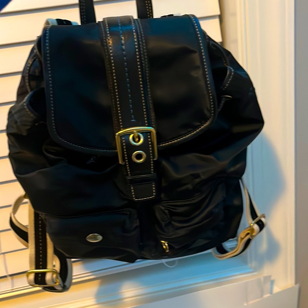 This is a black Coach backpack with gold details.